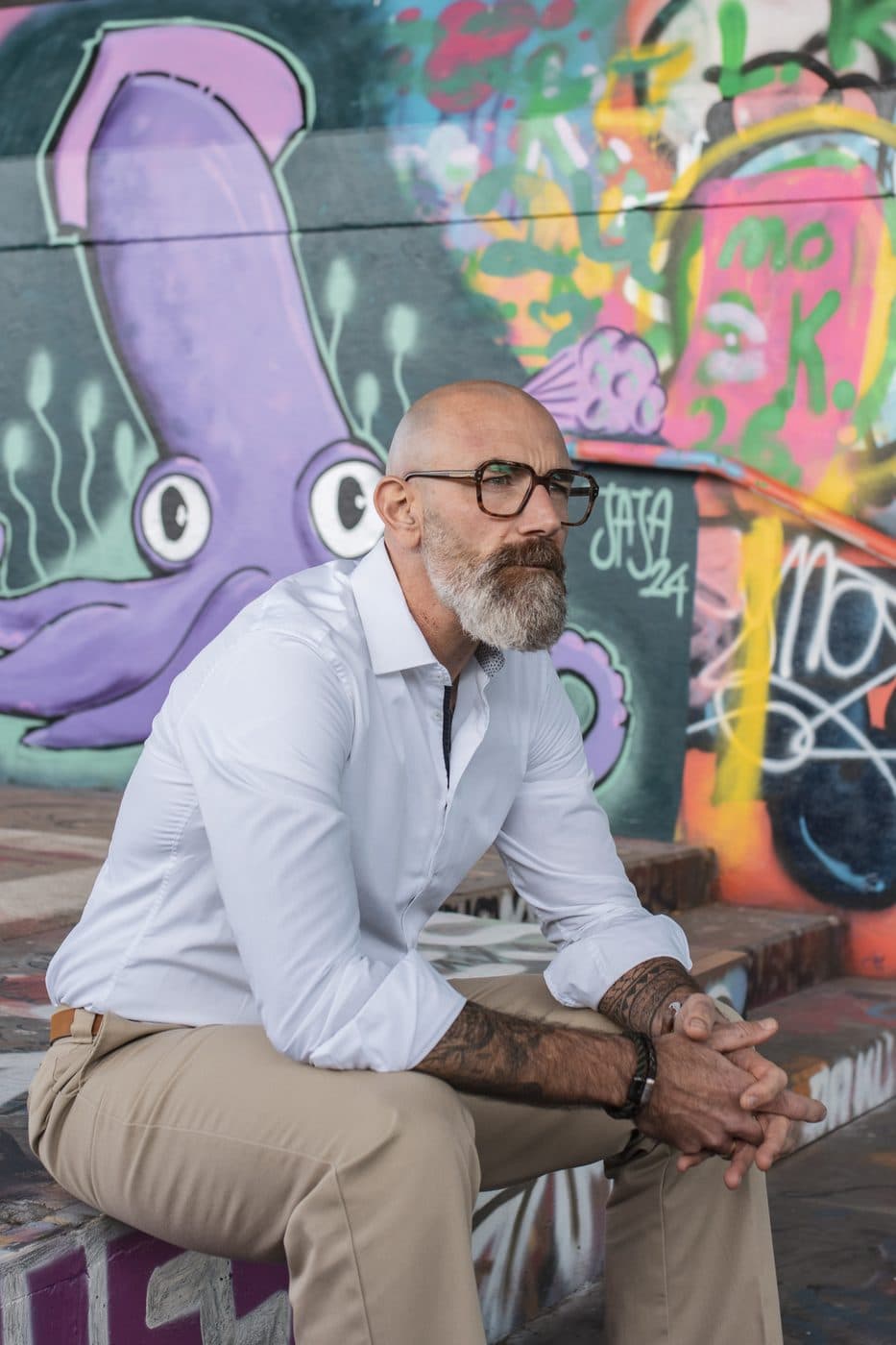 Tom Martens sitzt entspannt vor einer bunten Graffitiwand