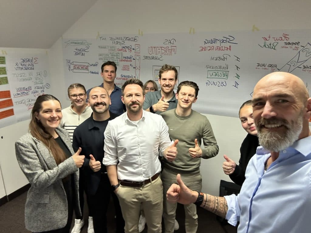 Gruppenfoto nach einem Vertriebstraining vor beschriebenen Flipcharts