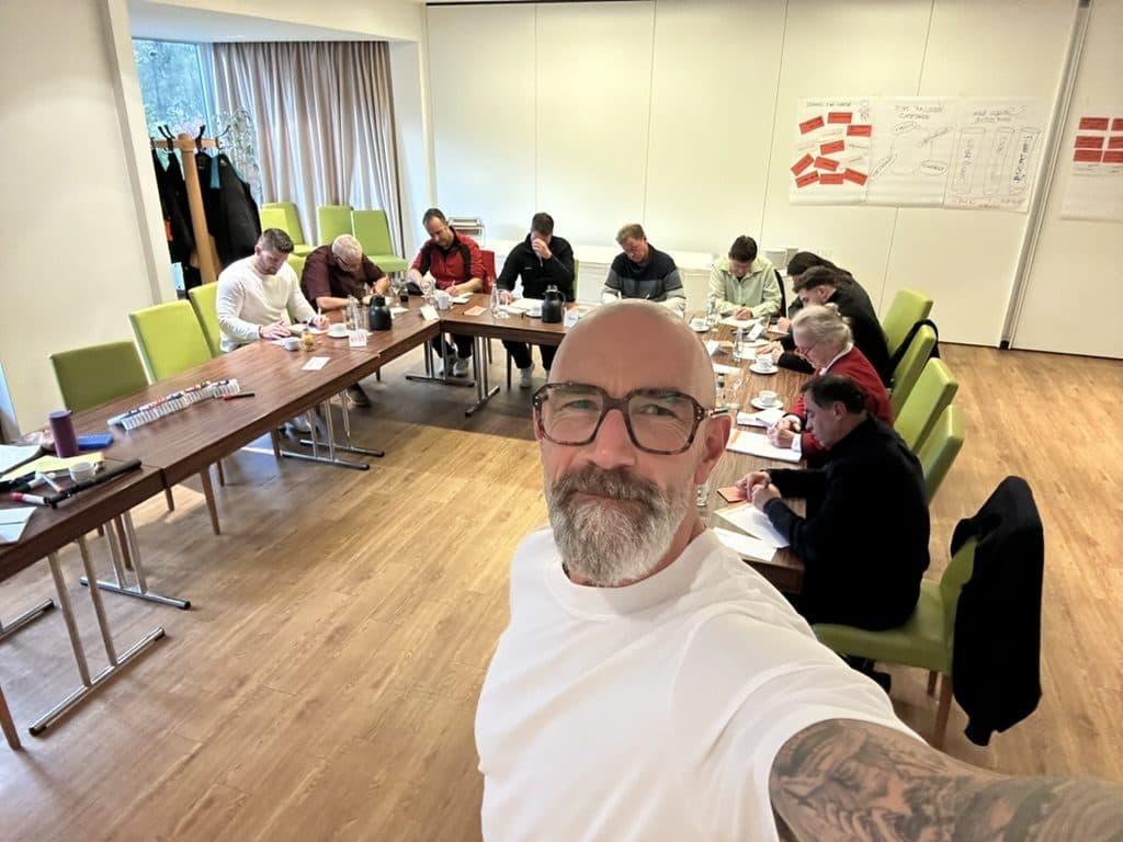 Tom Martens im Seminarraum, im Hintergrund die Gruppe an Tischen