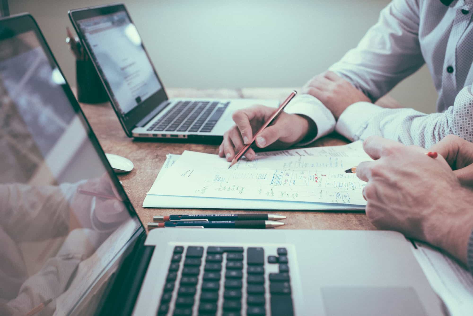 Analyse von Zahlen am Schreibtisch mit Laptop und Notizen